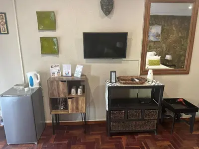 a living room with a television on a wall at Safari Bed & Breakfast in Hazyview