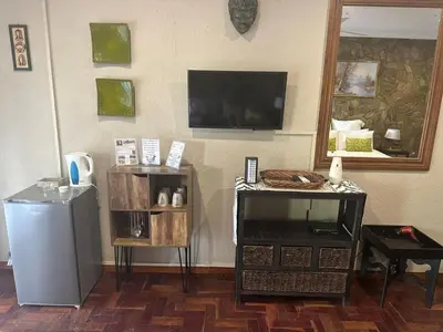 a living room with a television on a wall at Safari Bed & Breakfast in Hazyview