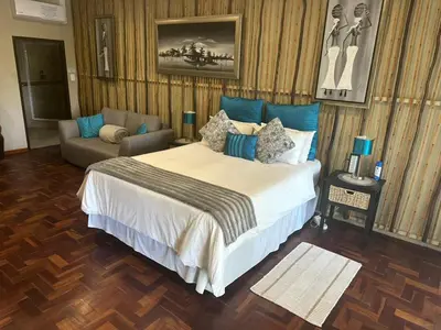 a bedroom with a large bed and a couch at Safari Bed & Breakfast in Hazyview