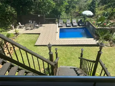 a swimming pool in a yard with chairs and a fence at Safari Bed & Breakfast in Hazyview