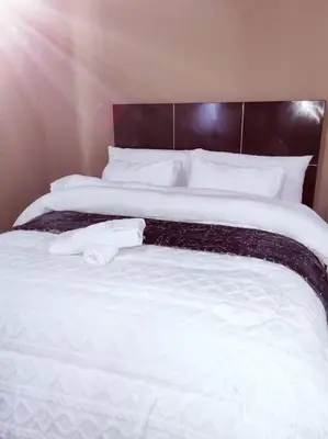 a bedroom with two beds with white sheets and pillows at ChoosersExpressHotel in Centurion