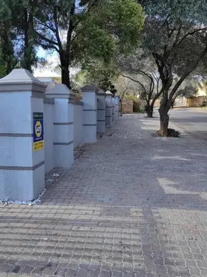 a brick sidewalk with a row of white fences at ChoosersExpressHotel in Centurion