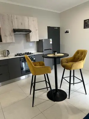 a kitchen with a table and two yellow chairs at Midrand E Airbnb in Midrand