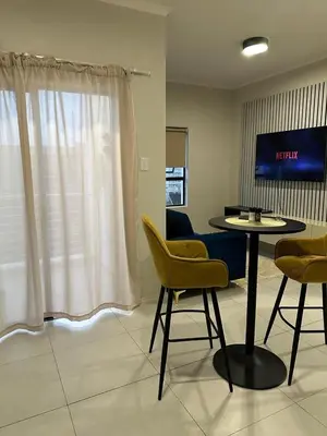 a room with a table and chairs and a tv at Midrand E Airbnb in Midrand