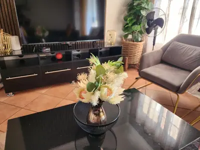 a living room with a vase with flowers on a table at Fern Valley in Pretoria