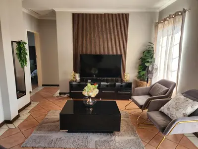 a living room with a large television and a table at Fern Valley in Pretoria