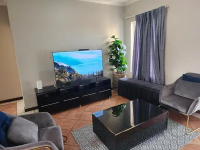 a living room with a couch and a flat screen tv at Fern Valley in Pretoria