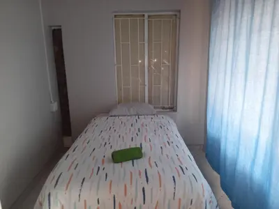 a small bed in a room with a window at Las Palmas Day & Night Guest House in Pretoria