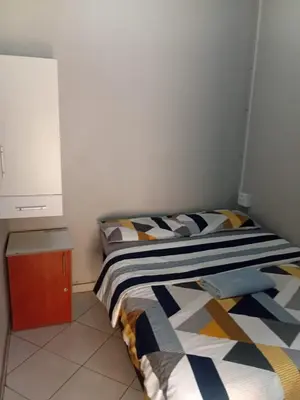 a small bedroom with a bed and a cabinet at Las Palmas Day & Night Guest House in Pretoria