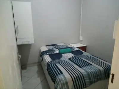 a small bedroom with a bed in a white room at Las Palmas Day & Night Guest House in Pretoria