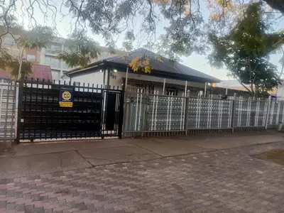 a white house with a gate and a fence at Las Palmas Day & Night Guest House in Pretoria