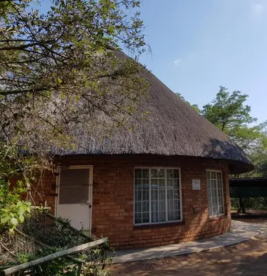 a small brick building with a thatched roof at Klein huisie in Marloth Park