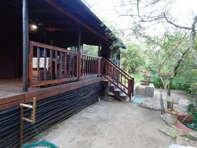 a porch of a wooden house with a staircase at Hout Huisie in Marloth Park