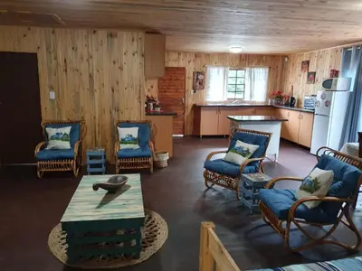 a living room with chairs and a table and a kitchen at Hout Huisie in Marloth Park