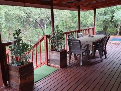 a wooden deck with a table and chairs on it at Hout Huisie in Marloth Park