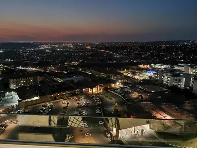a city at night with cars parked in a parking lot at Kashi Skyline: Live . Shop . Work . Play in Midrand