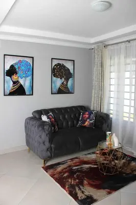a black couch in a living room with paintings at Tranquility at Homely Escape in Phalaborwa