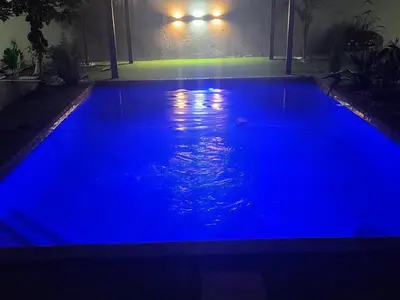 a large blue swimming pool at night at The Residence Villa in Musina