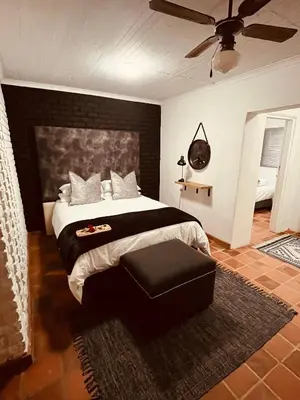 a bedroom with a large bed and a ceiling fan at The Hart House in Hartbeespoort