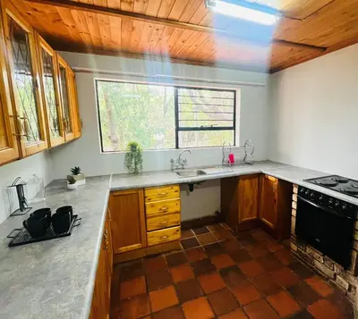 a kitchen with wooden cabinets and a sink and a window at The Hart House in Hartbeespoort