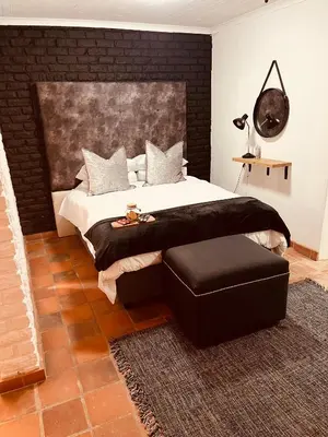 a bedroom with a large bed and a ottoman at The Hart House in Hartbeespoort