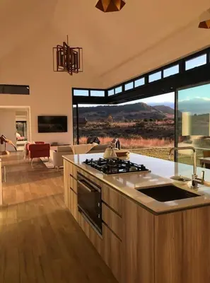 a kitchen with a stove top oven next to a living room at Walkersons Estate- Outcrop in Dullstroom