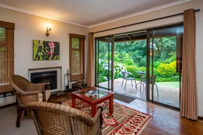 a living room with a fireplace and a table and chairs at Kuhestan Farm Cottages in Haenertsburg
