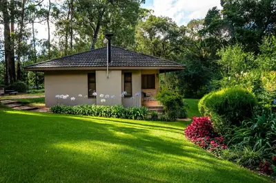 a small house in a yard with a green lawn at Kuhestan Farm Cottages in Haenertsburg