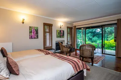 a bedroom with a bed and a desk and a window at Kuhestan Farm Cottages in Haenertsburg