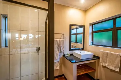a bathroom with a shower and a sink at Kuhestan Farm Cottages in Haenertsburg
