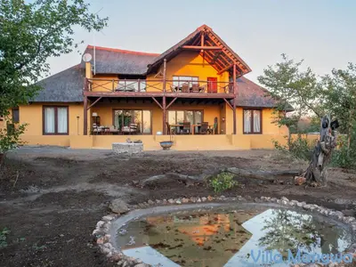 a house with a pond in front of it at Kruger Wildlife Villas in Phalaborwa