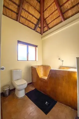 a bathroom with a wooden tub and a toilet at Kruger Wildlife Villas in Phalaborwa