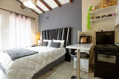 a bedroom with a bed and a desk and a television at Relax in Nature Cottage Close to OR Tambo International Airport in Kempton Park