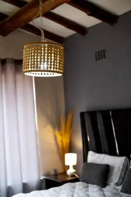 a bedroom with a chandelier and a bed and a lamp at Relax in Nature Cottage Close to OR Tambo International Airport in Kempton Park