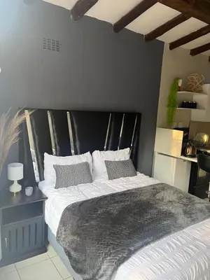 a bedroom with a large bed with a black headboard at Relax in Nature Cottage Close to OR Tambo International Airport in Kempton Park