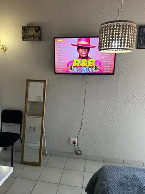 a flat screen tv on the wall of a bedroom at Relax in Nature Cottage Close to OR Tambo International Airport in Kempton Park