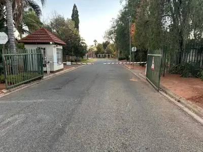 an empty street with a gate and a house at Relax in Nature Cottage Close to OR Tambo International Airport in Kempton Park