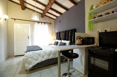 a bedroom with a bed and a desk and a television at Relax in Nature Cottage Close to OR Tambo International Airport in Kempton Park