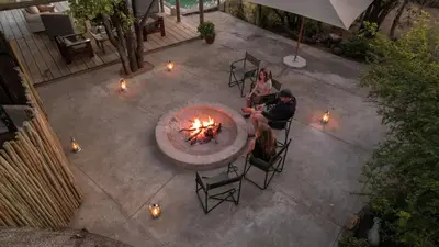 a group of people sitting around a fire pit at Nsala Wilderness Camp in Timbavati Game Reserve