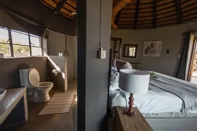 a bedroom with a bed and a bathroom with a toilet at Nsala Wilderness Camp in Timbavati Game Reserve