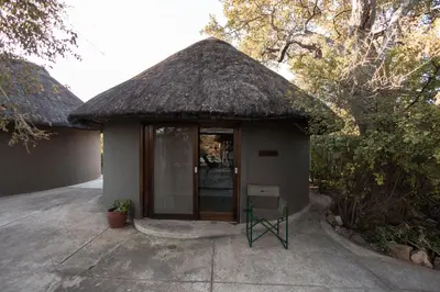 a small building with a thatched roof and a chair at Nsala Wilderness Camp in Timbavati Game Reserve