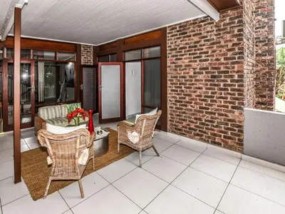 a patio with chairs and a couch on a brick wall at An Exclusive Guesthouse too in Nelspruit
