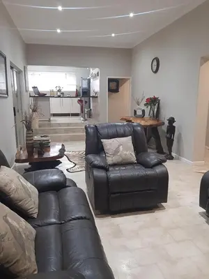 a living room with a leather couch and a table at Leadwood Guesthouse in Tzaneen