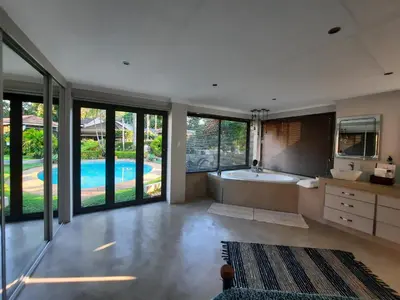 a bathroom with a tub and a swimming pool at Leadwood Guesthouse in Tzaneen