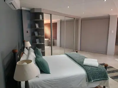 a bedroom with a bed with a green blanket and a lamp at Leadwood Guesthouse in Tzaneen