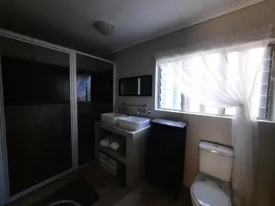 a bathroom with a toilet and a sink and a window at Leadwood Guesthouse in Tzaneen
