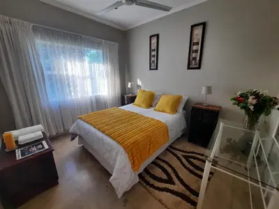 a bedroom with a bed with yellow pillows and a window at Leadwood Guesthouse in Tzaneen