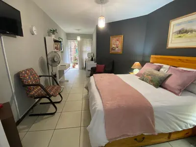 a bedroom with a large bed and a chair at Serene Garden Suite in Pretoria