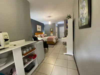 a small room with a bed and a room with a kitchen at Serene Garden Suite in Pretoria