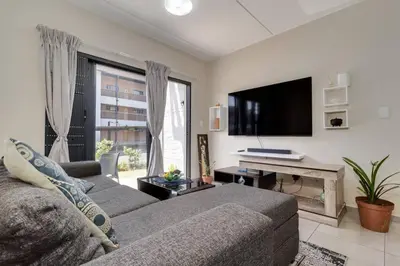 a living room with a couch and a flat screen tv at GroundEazy beside Mall of Africa in Midrand